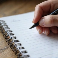 Persona che scrive in un quaderno con una penna